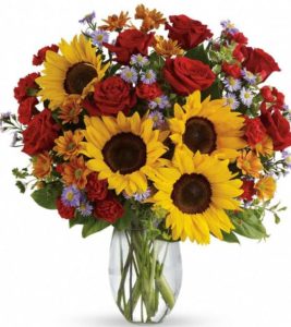 sunflowers and red roses with assorted floral accents in vase