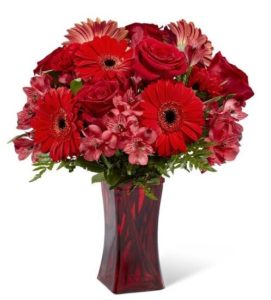 Ready to celebrate any of life's special moments, this daring bouquet weaves together rich red roses, red gerbera daisies, red carnations, and red Peruvian Lilies with lush greens to create a simply unforgettable gift of flowers. Presented in a modern red glass vase to add to the drama of this arrangement, this flower bouquet is set to send your thinking of you, happy birthday, or, "I love you," wishes across the miles.