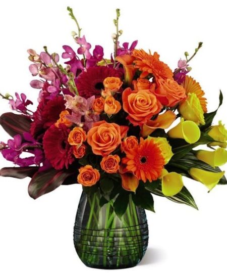 A floral arrangement to a celebrate color and design that brings energy, radiant beauty, and unmatched elegance to your special recipient's every day. Handcrafted with an expert eye and consciously on trend with an impressive Ombre look and feel. Showcasing a sophisticated transition in colors capturing the eye first with the bright pink mokara orchids, folding into the deep red gerbera daisies, and then melding into the bright orange roses, and vibrant yellow calla lilies, this floral arrangement is meant to express joy with its modern design appeal.