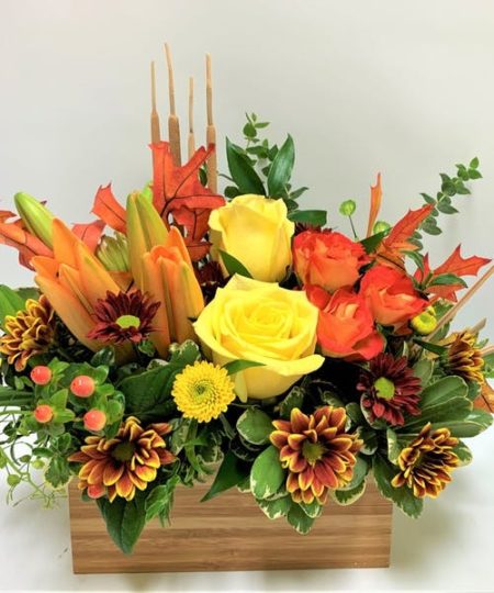 Bold beauty of bright roses and lilies surrounded by fall flowers, captures every expression of autumn joy. Complete with bursts of fall daisy, yellow button pompoms, this arrangement is set in a modern tan bamboo container to accent any home. Gift this bouquet for a fall birthday, holiday gathering or simply just because, it will surely brighten their day!