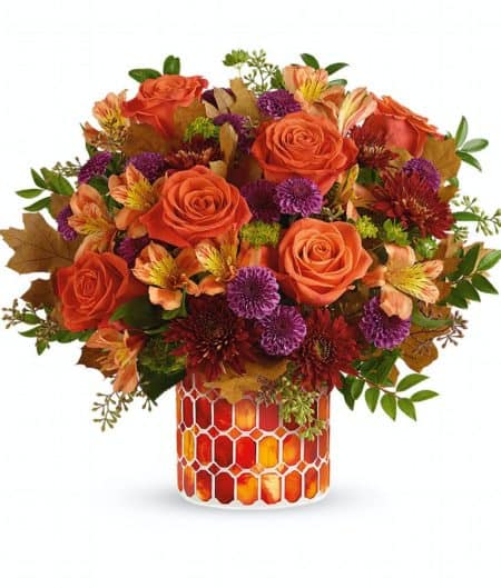 Radiant roses and lush fall blooms are presented to perfection in a keepsake mosaic vase of stunning stained glass. This radiant arrangement includes roses, alstroemeria, button spray chrysanthemums, cushion spray chrysanthemums, bupleurum, seeded eucalyptus and huckleberry, accented with transparent oak leaves. Delivered in Autumn Radiance Mosaic cylinder vase. Approximately 14 1/4" W x 13" H